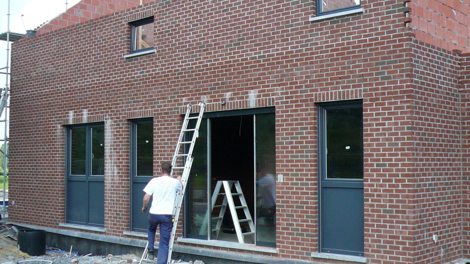 Maison neuve — châssis et volets anthracite sur briques rouges